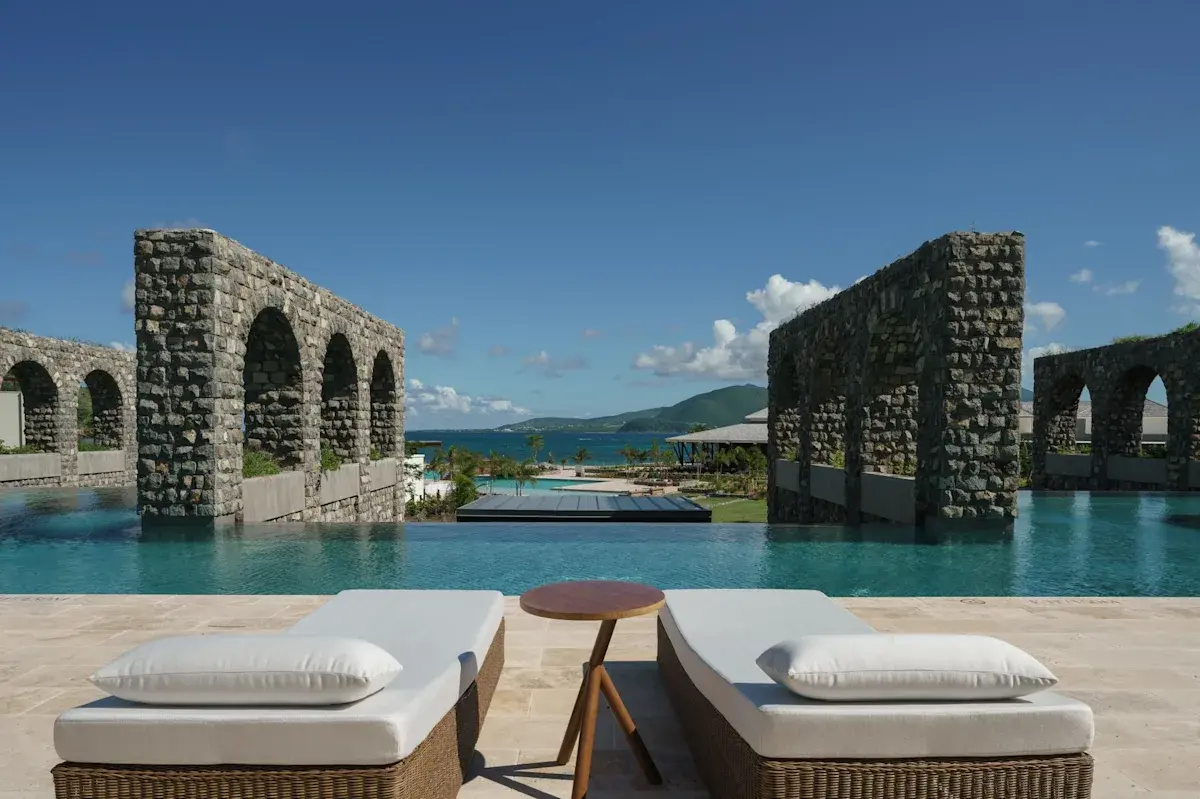 Two gray daybeds near a pool overlooking the ocean