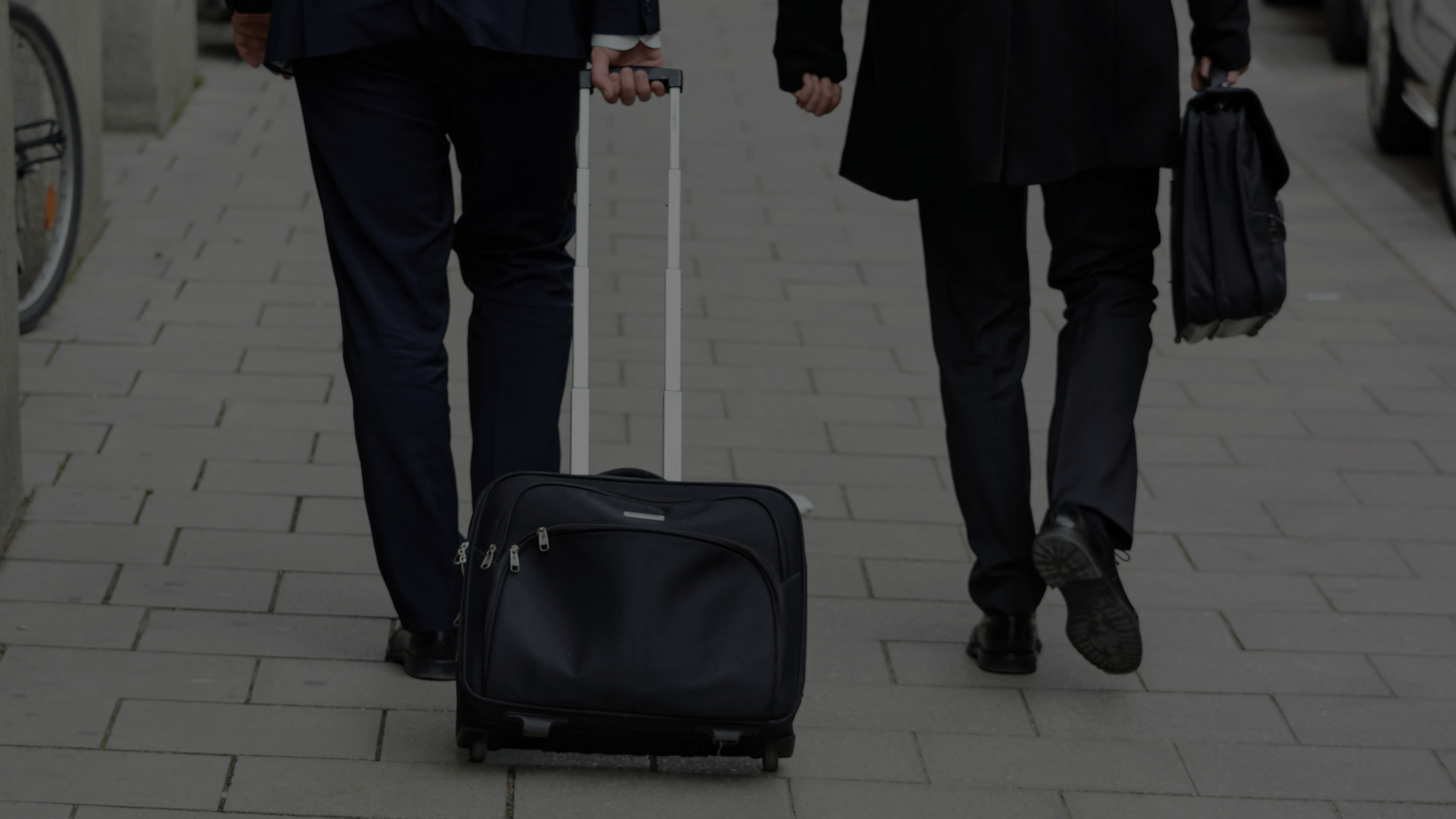 Business travelers walking with rolling luggage and a briefcase on a corporate trip