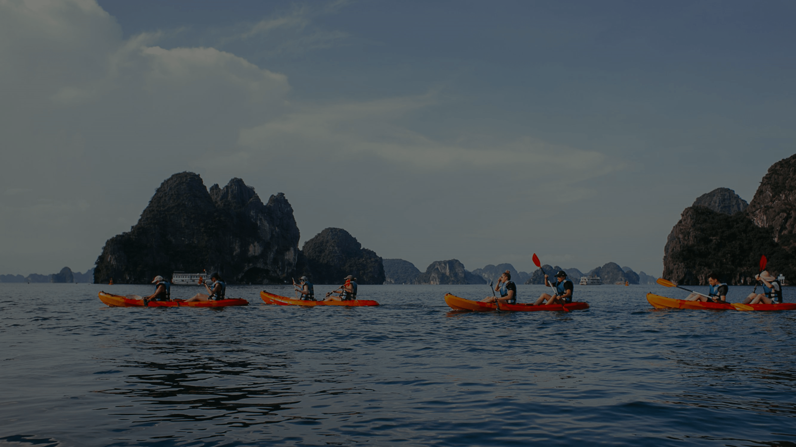 Group of travelers kayaking among limestone islands at dusk