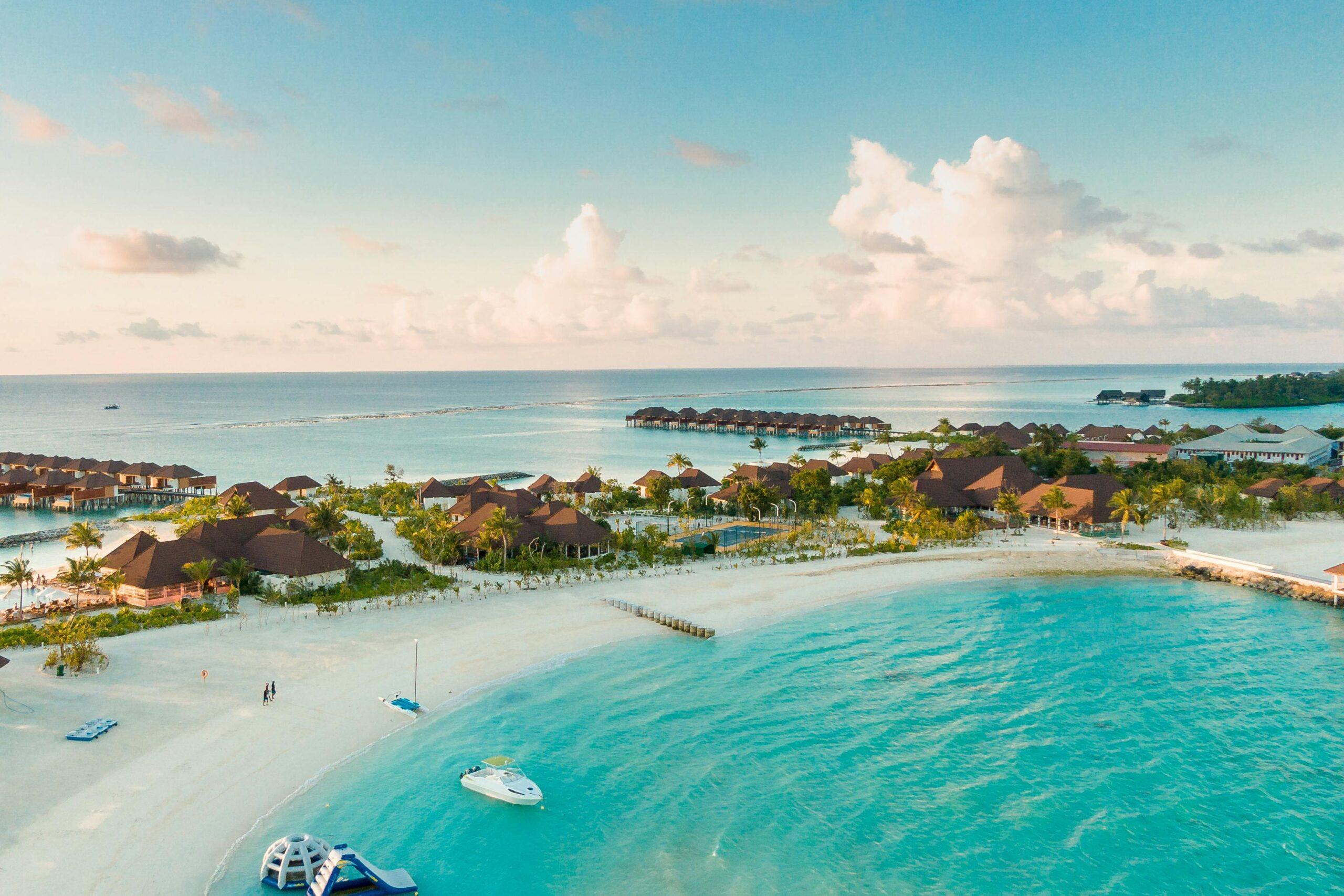 Aerial view of a tropical island resort with overwater villas and turquoise water