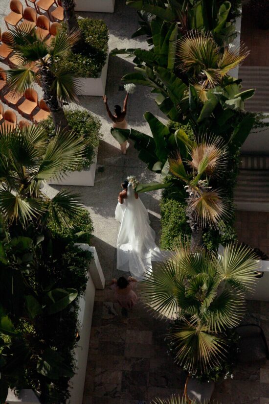 Bride crossing a palm-lined resort courtyard at her destination wedding venue