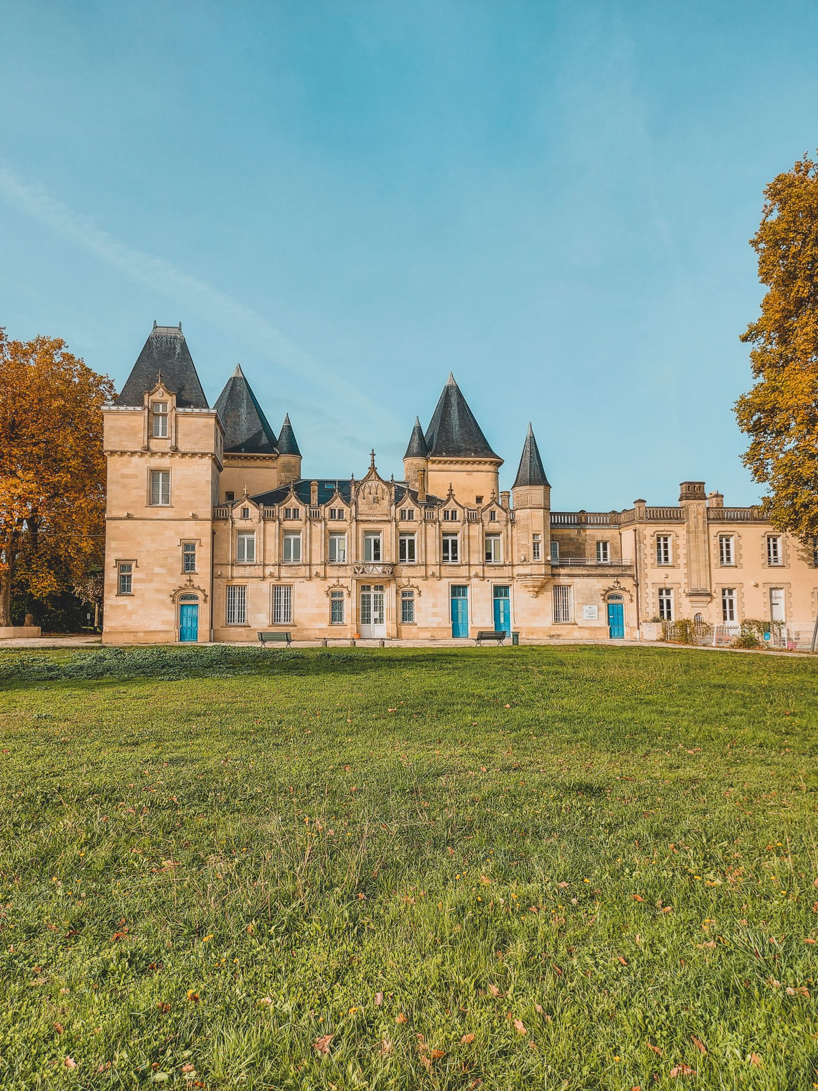 Historic Bordeaux château with slate turrets and autumn trees on a luxury French wine tour