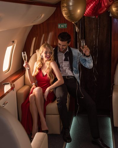 beautiful young couple with champagne sitting in airplane